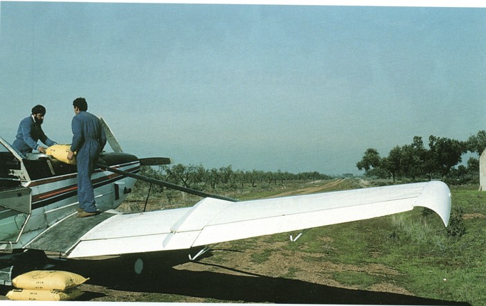 Dos cargadores vaciando sacos de abono en la tolva de la avioneta