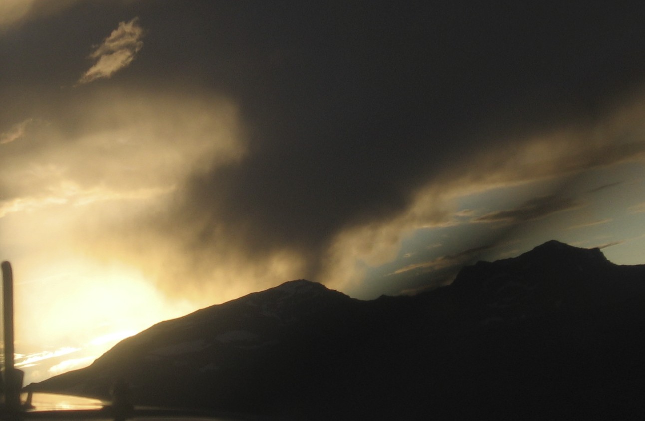 Amanecer con la columna de humo del incendio recortando las montañas