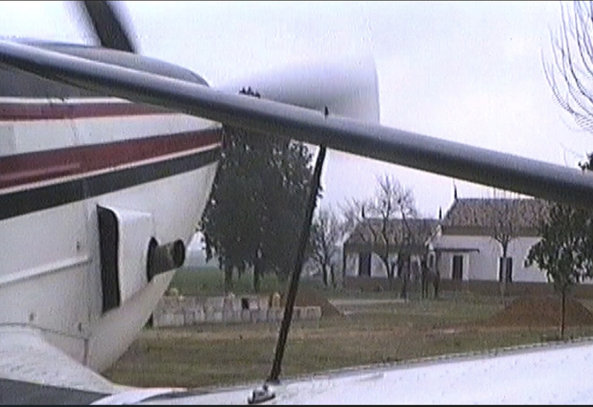 Vista desde la cabina de la avioneta en tierra, junto a un cortijo blanco