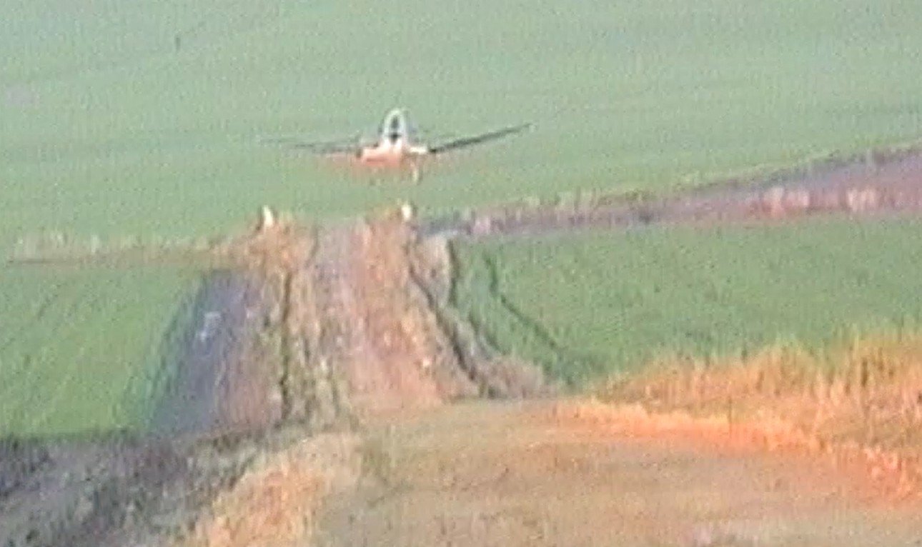 Avioneta aproximándose para aterrizar en un camino de tierra embarrado entre sembrados